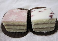 two pieces of cake sitting on top of each other with white frosting and pink toppings