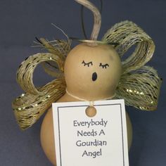 a wooden doll with a sign that says everybody needs a gourdian angel