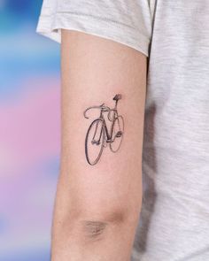 a woman's arm with a bicycle tattoo on the left side of her arm