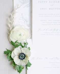 the wedding stationery is decorated with white flowers and greenery