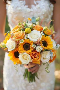 a bride holding a bouquet of sunflowers and roses