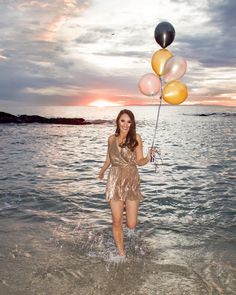 a woman is standing in the water with balloons