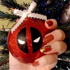 someone holding up a red ornament with a deadpool on it's face