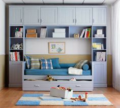 a living room with blue furniture and bookshelves on the wall, including a couch