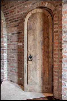 an old wooden door in the middle of a brick wall with a round handle on it