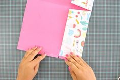 someone cutting out paper with scissors on top of a piece of crafting material that has been cut into smaller pieces