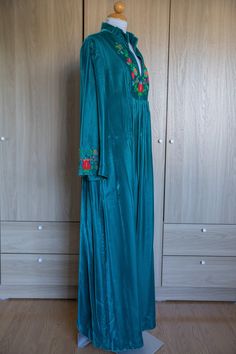 "A dreamy split collar maxi with floral yarn embroidery at the chest. The dress is velvety smooth and the sleeves are belled and feature embroidery as well! No label, best fits on a Large and Tall person. Not sure if it was made in the 70's although vintage this item looks barely worn! Measurements: Shoulder 16.5\" Sleeve 23\" Pit to Pit 21\" Waist 19\" Length 56\"" Festive Maxi Dress With Embroidered Neckline, Festive Long Sleeve Maxi Dress With Floral Embroidery, Party Maxi Dress With Embroidered Neckline, Floral Embroidered Maxi Dress For Festive Occasions, Festive Long Maxi Dress With Floral Embroidery, Festive Floral Embroidered Maxi Dress, Festive Floral Embroidery Maxi Dress, Velvet Bohemian Dress For Holiday Season, Festive Bohemian Velvet Dress