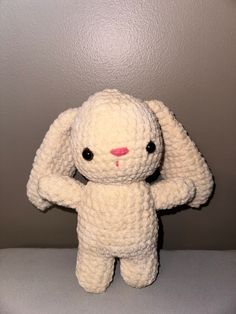 a crocheted white stuffed animal sitting on top of a table next to a wall