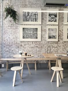 a brick wall with pictures hanging on it and two wooden chairs in front of the table