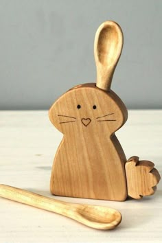 a wooden toy rabbit sitting next to a spoon