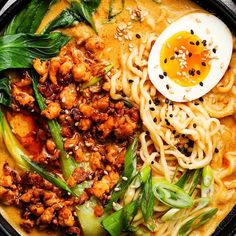 a bowl filled with noodles, meat and vegetables next to an egg on top of it