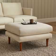 a coffee table sitting on top of a foot stool in front of a white couch