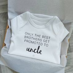 a white onesie with the words uncle on it sitting next to a pair of scissors