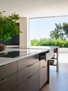 a modern kitchen with an island countertop and large windows looking out onto the outdoors