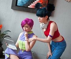 two women in colorful outfits are looking at a laptop