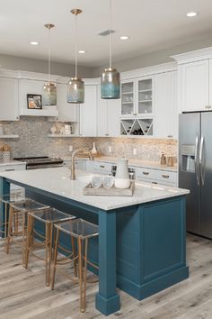 a kitchen with white cabinets and blue island