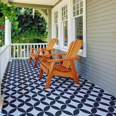 two wooden chairs sitting on top of a black and white floor next to a porch