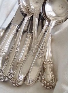 an assortment of antique silverware on a white cloth with the rest of it's forks and spoons