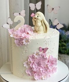 a white cake decorated with pink flowers and butterflies