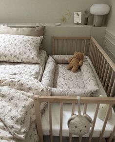 a baby crib with a teddy bear in it and pillows on the bottom bed