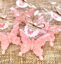 some pink butterflies are sitting on a table with tags attached to the back of them