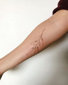 a woman's arm with a tattoo that has a leaf design on the side