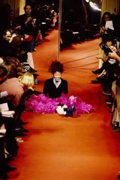 a person sitting in the middle of a runway surrounded by people taking pictures with their cell phones