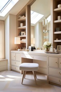 a white vanity with a stool in front of it and a large mirror on the wall