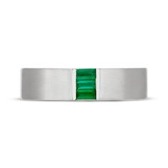 a white gold ring with an emerald colored stone in the center and two horizontal bands on each side