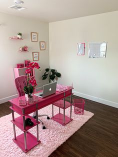 a pink desk with a laptop on it in a room that has hardwood floors and white walls