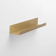 a gold metal shelf mounted to the side of a wall with two hooks on it