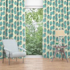 a living room with blue curtains and a chair in front of a window that has green leaves on it