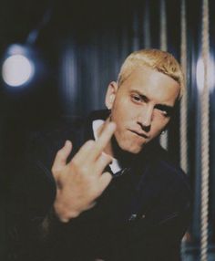 a man with blonde hair pointing at the camera