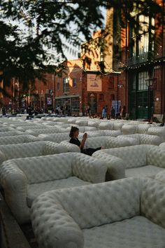 a woman laying on top of white couches in the middle of a city street