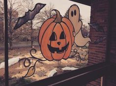 a window decorated for halloween with pumpkins and ghost