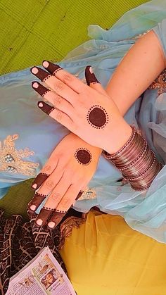 a woman with henna tattoos on her hands and arm, sitting in a blue dress