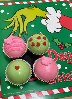 four cupcakes with pink frosting and green icing on a christmas card