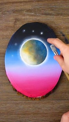 a person is painting a cake with pink and blue frosting on top of it