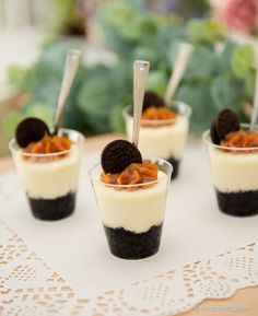 four desserts with oreo cookies and cream in small cups on a doily