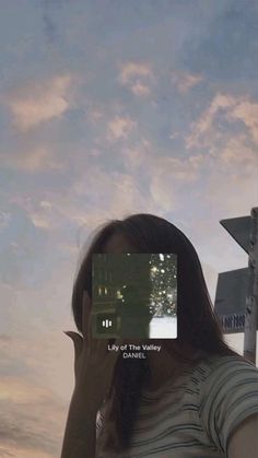 a woman is holding up her cell phone to take a selfie with the sky in the background