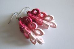 several pairs of pink and white earrings on a white surface with one pair dangling from the back