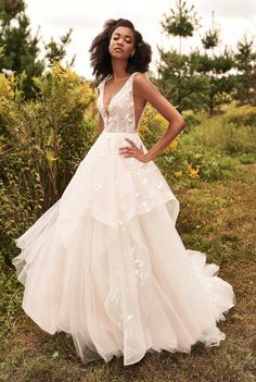 a woman wearing a wedding dress standing in the grass