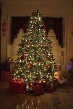 a lit christmas tree with presents under it