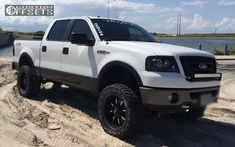 a white truck parked on top of a sandy beach