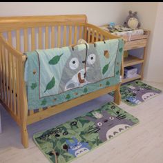 a baby crib with two rugs on the floor next to it and an animal themed bedding