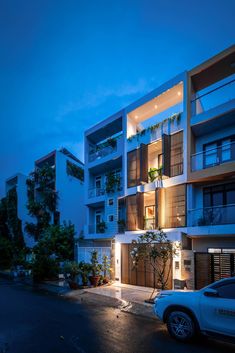 an apartment building at night with cars parked on the street