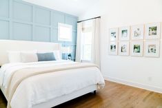 a white bed sitting in a bedroom next to a window with pictures on the wall