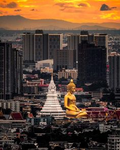 a buddha statue sitting on top of a building in the middle of a large city