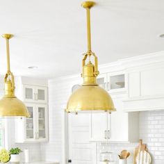 two brass pendant lights hanging over a kitchen island