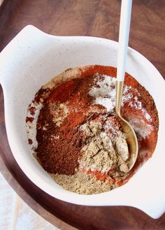 a bowl filled with spices and powder on top of a wooden table